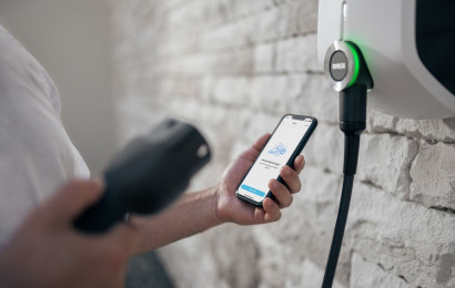 Une personne démarre une charge avec son téléphone portable à côté d'une station de recharge domestique EVBox Elvi.
