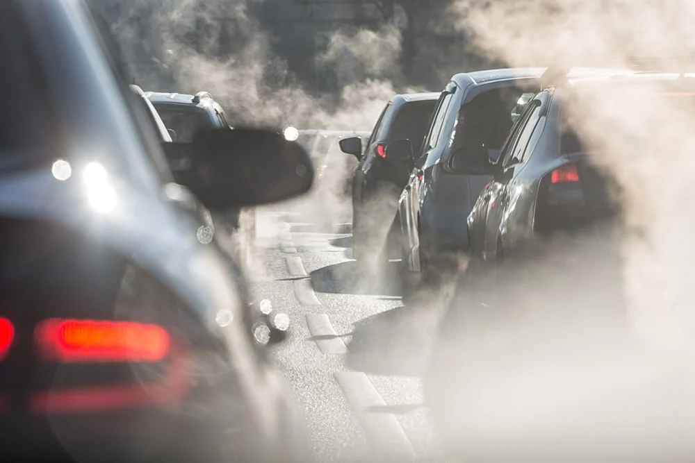 Tráfico denso de coches con humo y contaminación.