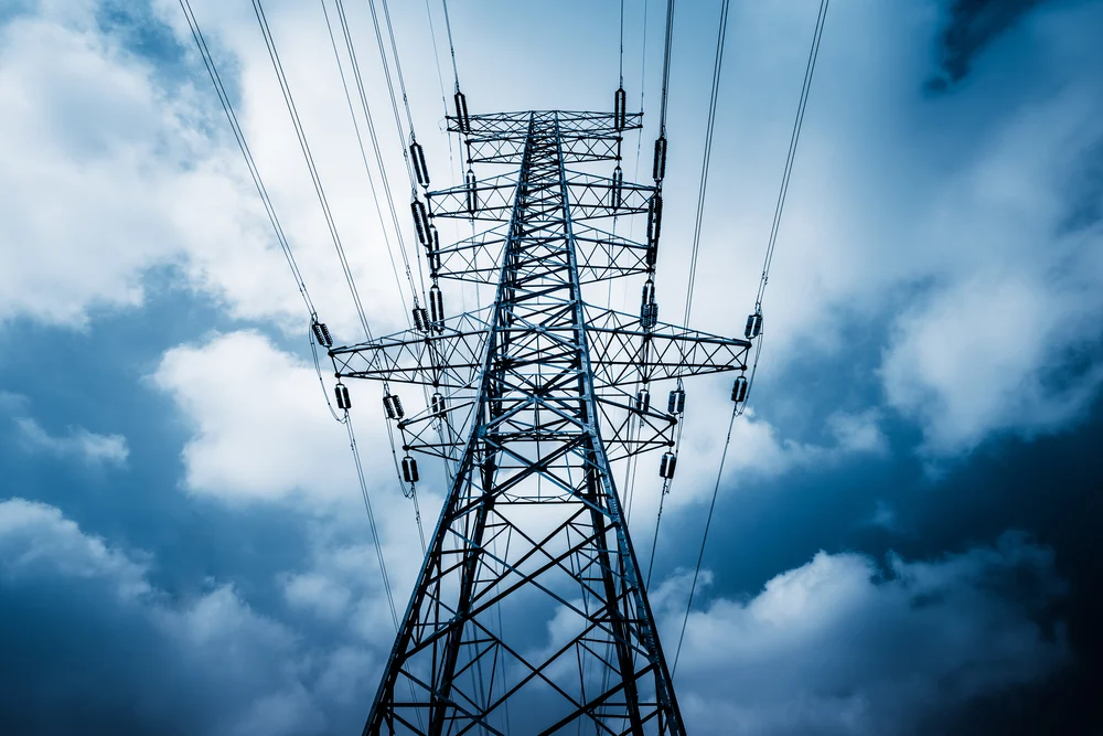 A professional photo of a high-voltage tower with clouds in the background.