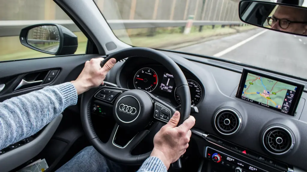 Conductor al volante de un Audi con GPS visualizado en la pantalla del vehículo.