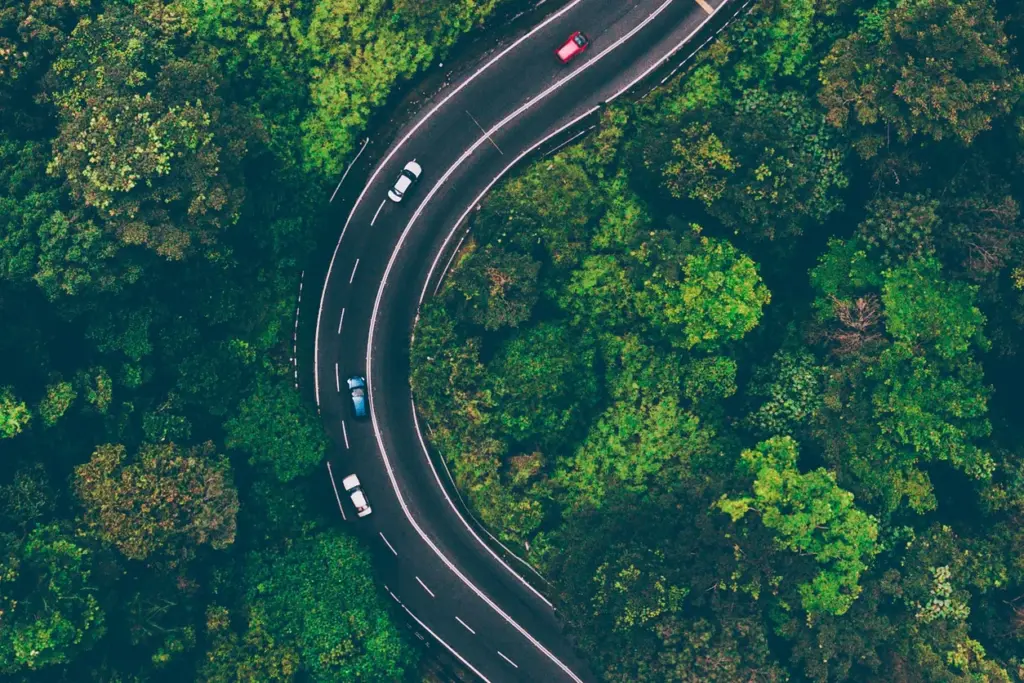 An arial shot of a winding three-lane highway in the forest.