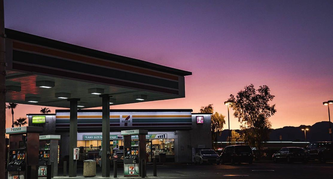 En tom bensinstasjon med en nærbutikk i solnedgangen.
