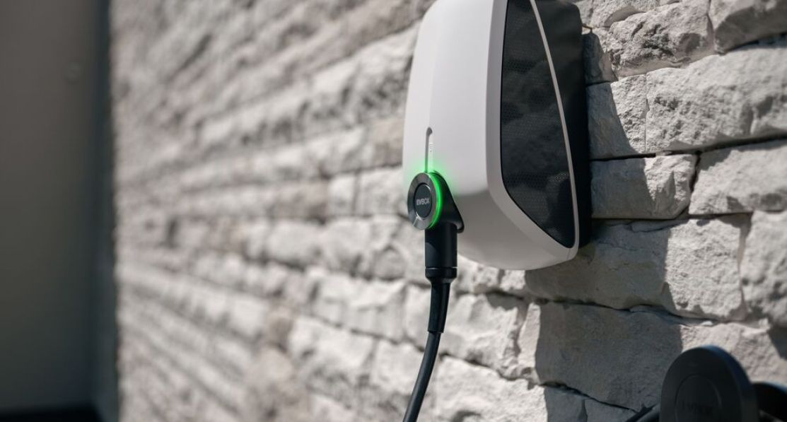 An Elvi home charging station is mounted on a brick wall.