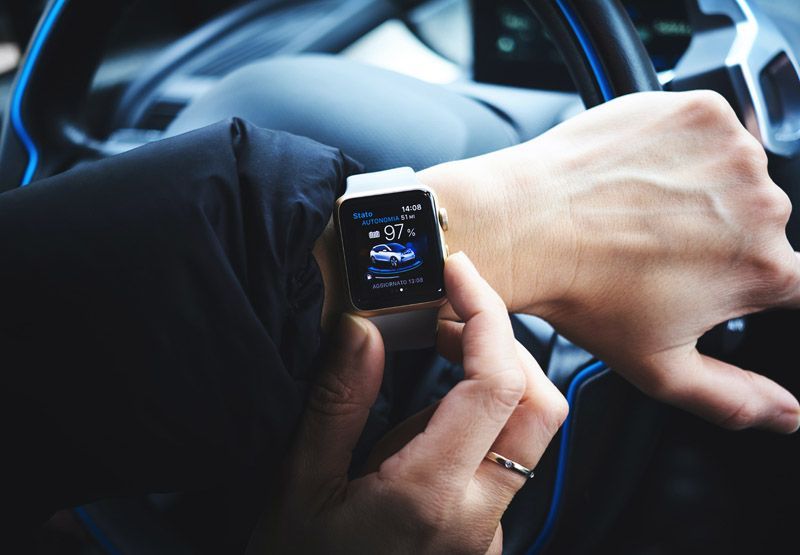 En gift EV-förare som kontrollerar statusen på bilens batteri på sin smartwatch. Klockan visar att batteriet är 97 % fullt.
