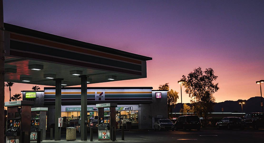 En tom bensinstation med en närbutik i solnedgången.