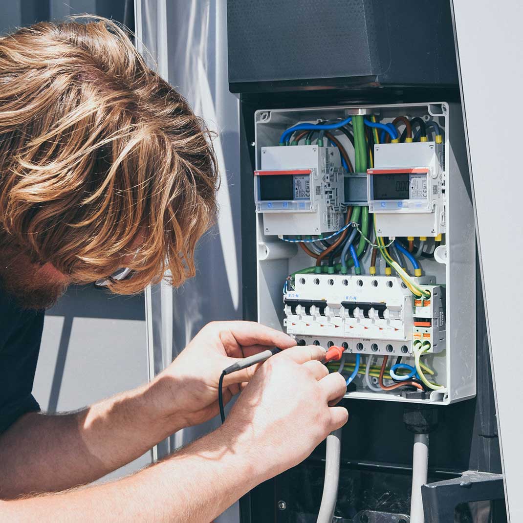 En installatör som kopplar ihop kablar inuti en laddstation.