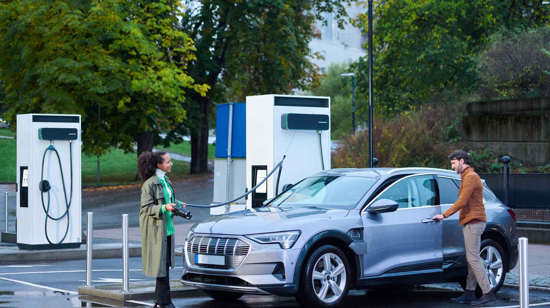 Man and woman standing next to car while charging with EVBox Troniq Modular