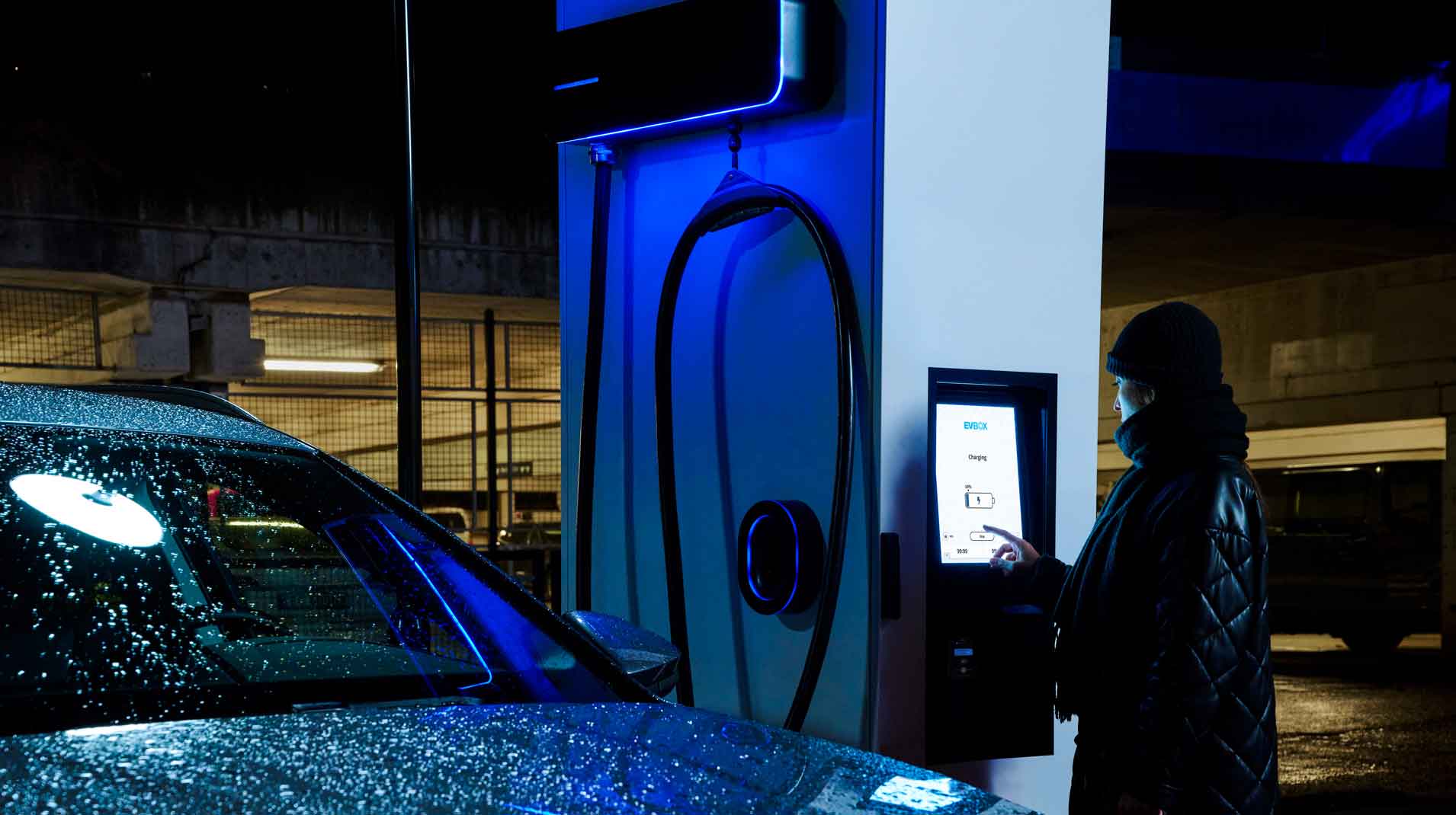 A person using an EVBox Troniq Modular fast charging stations at night