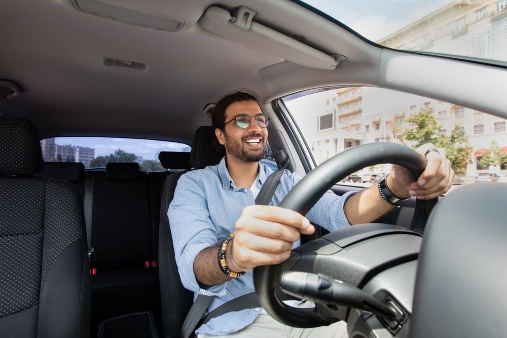 Man smiling while driving car.