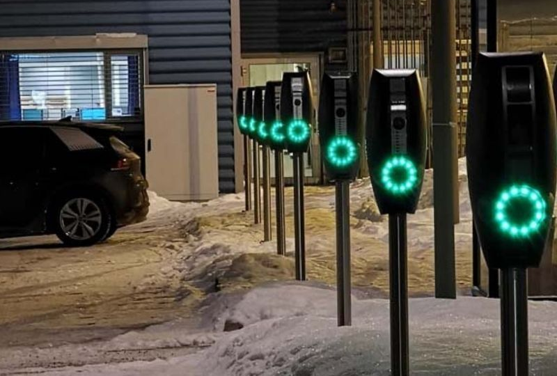 A line of EVBox BusinessLine charging stations lit up at night in a snowy carpark