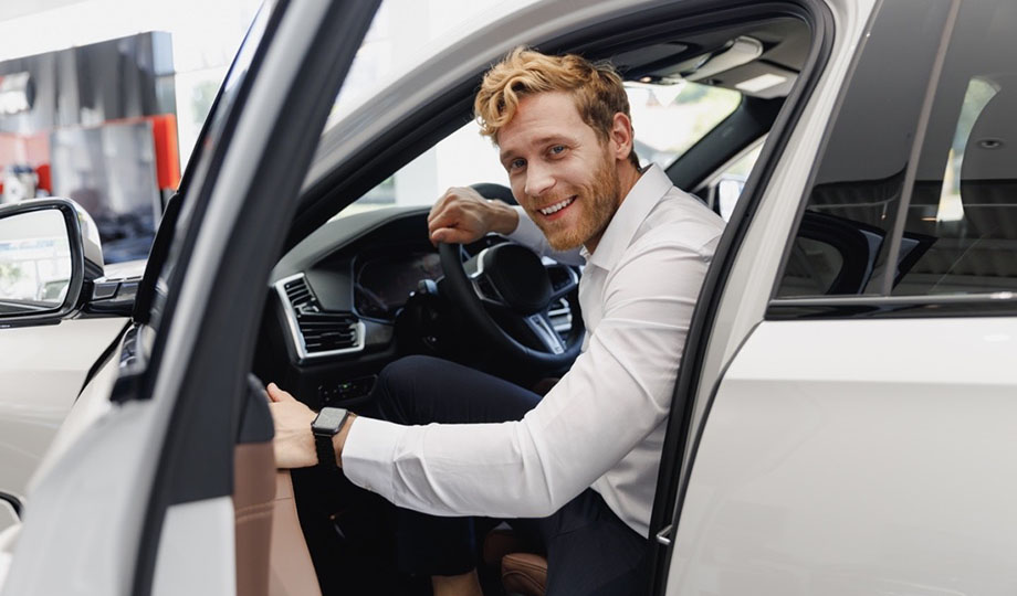 A man smiling is happy to drive his electronic vehicle.