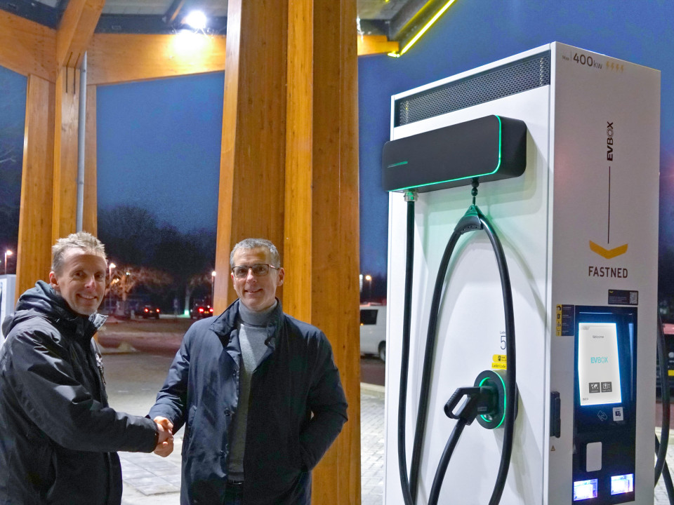 EVBox en Fastned medewerkers schudden handen naast een EVBox Troniq High Power laadstation.