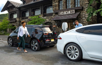 Man and woman charging electric vehicles outside a hotel