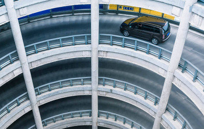 A circular parking ramp that has multiple levels with a car driving on it.