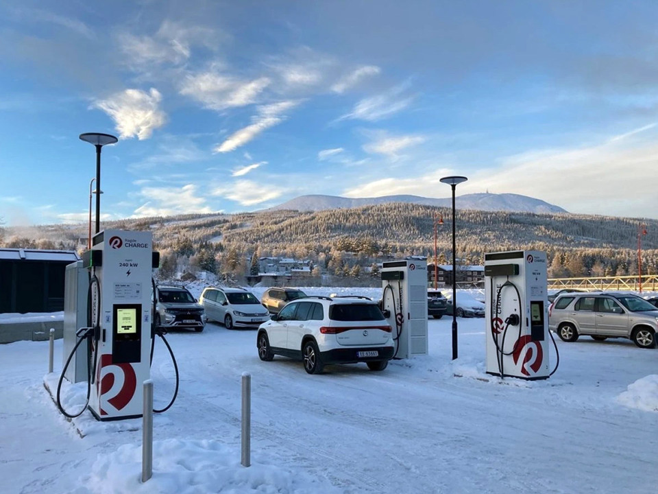 Quatre stations de recharge rapide EVBox Troniq Modular dans la neige avec une montagne en arrière-plan