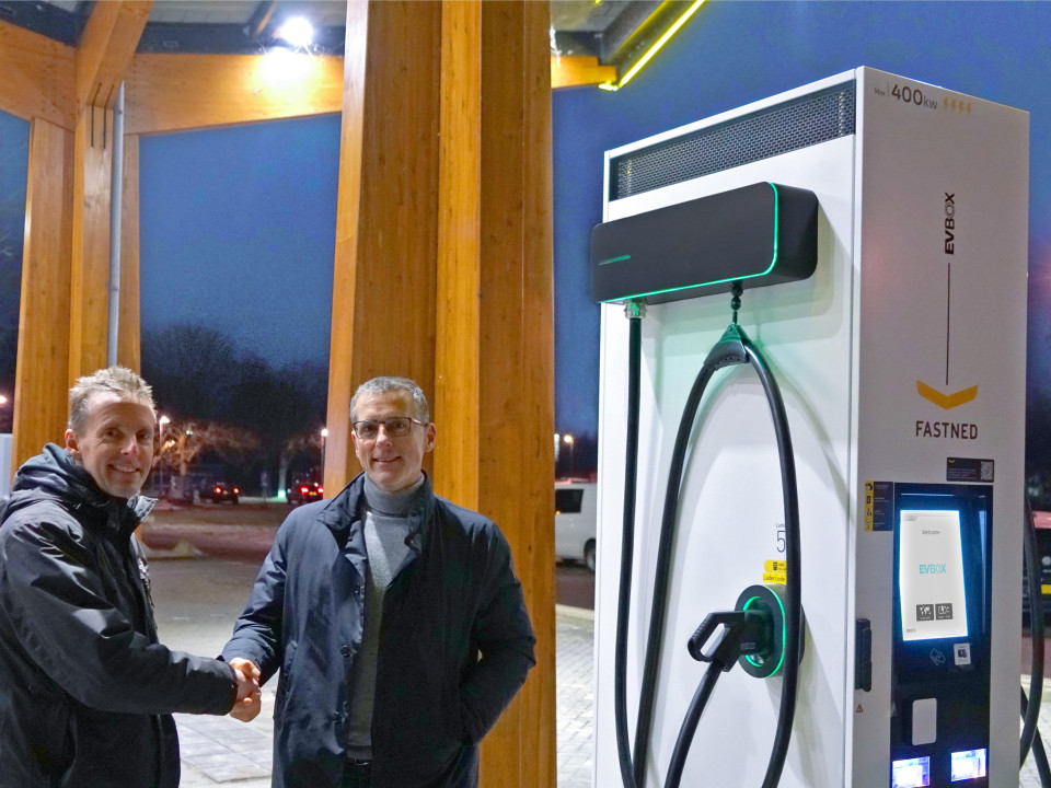 two men shaking hands in front of an EVBox charging station