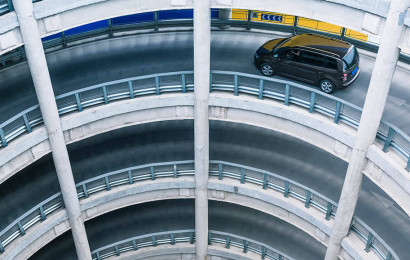 Une rampe de parking circulaire à plusieurs niveaux sur laquelle circule une voiture.