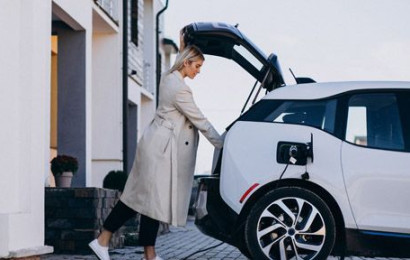 Una mujer cargando el baúl de su coche eléctrico mientras se carga.