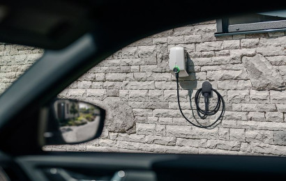 Eine EVBox Elvi Ladestation, die an einer Steinwand montiert ist, ist durch das Fenster eines Autos zu sehen.
