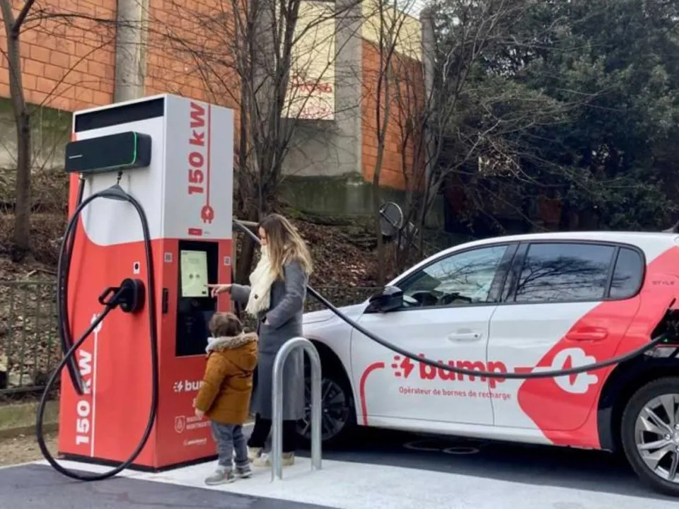 Eine Frau, die das Kabel einer EVBox-Ladestation an ihr Auto anschließt