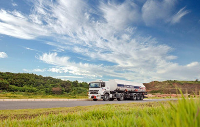En tung lastebil kjører på en landevei på en solfylt dag.