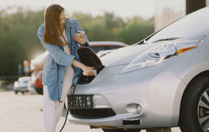 A woman plugs her car into a charging station.