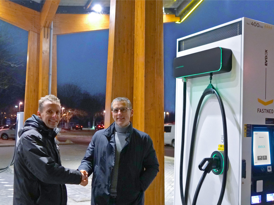two men shaking hands in front of an EVBox charging station