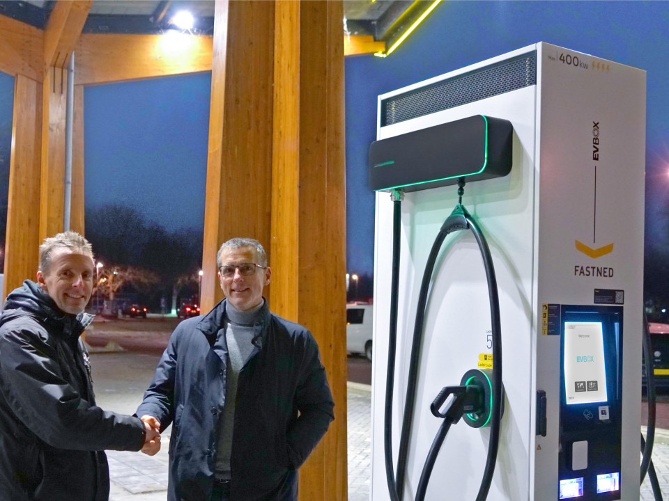 EVBox and Fastned employees shaking hands beside an EVBox Troniq High Power charging station