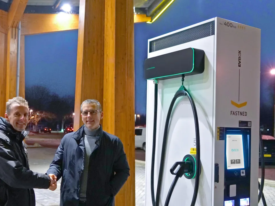 two men shaking hands in front of an EVBox charging station