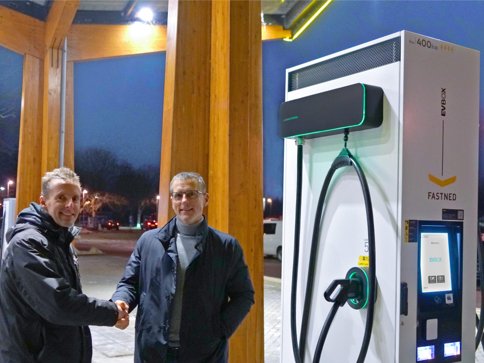 two men shaking hands in front of an EVBox charging station