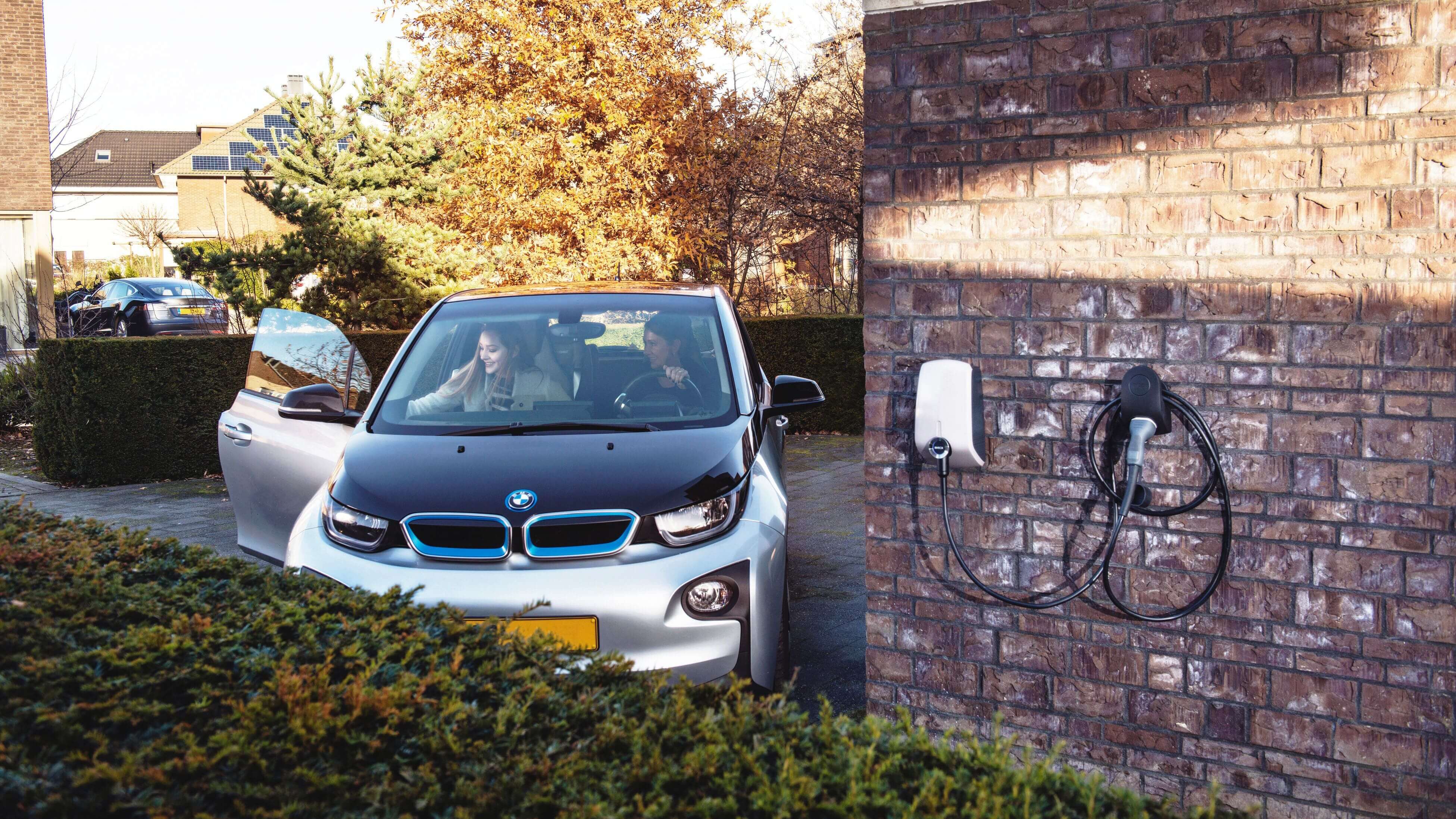 Wall mounted EVBox Elvi home charging station next to a parked car