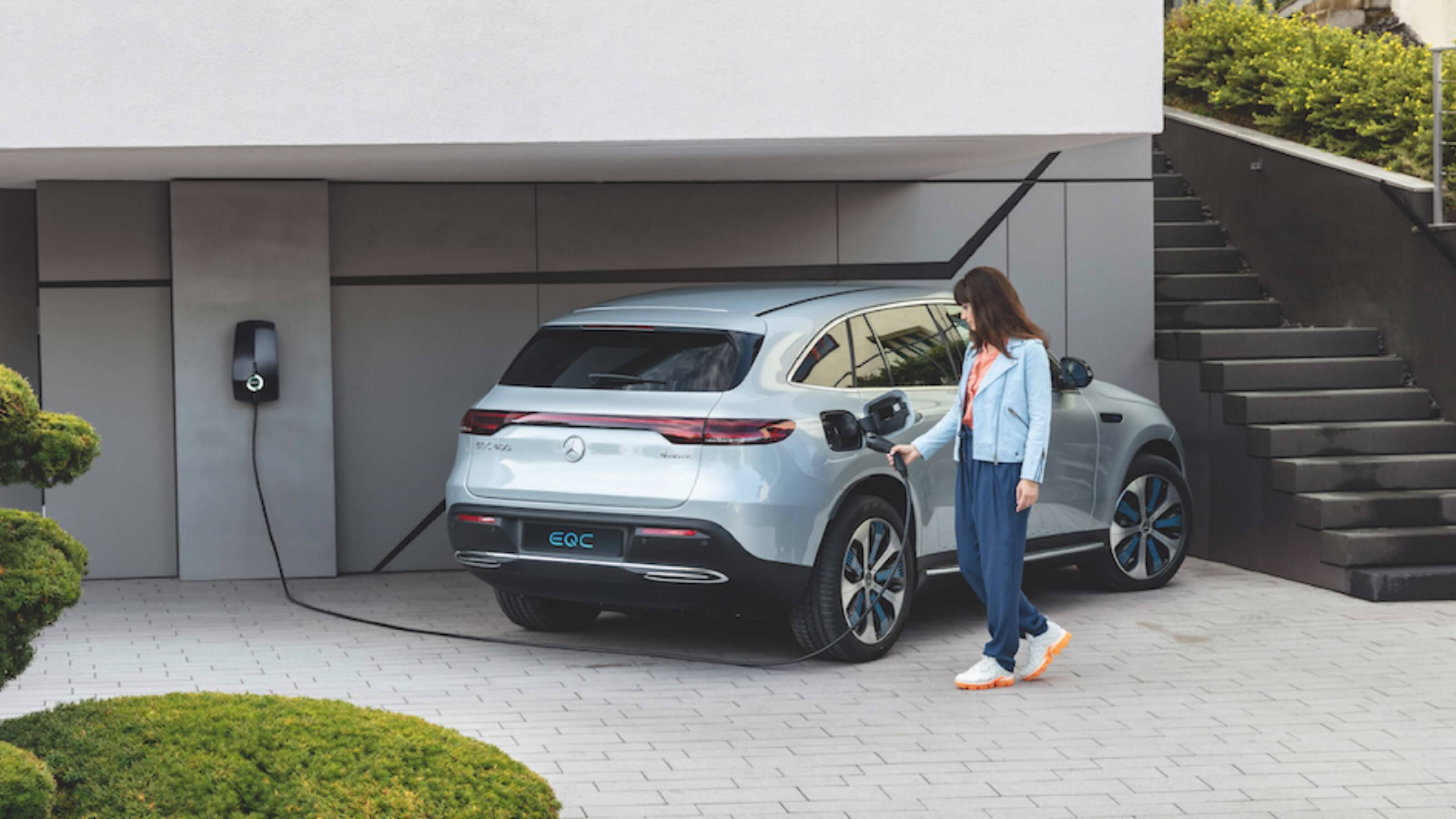 Woman charging her car in a driveway using an EVBox Elvi charging station